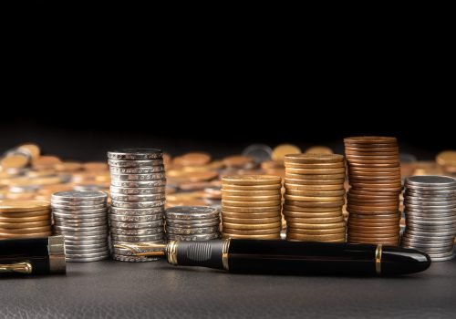 Coins, Brazilian coins of various amounts piled up and a fountai Coins, Brazilian coins of various amounts piled up and a fountain pen on black leather, selective focus.
