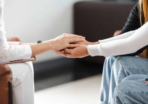 Psychologist holding hands and provide assistance understanding problems of a woman patient